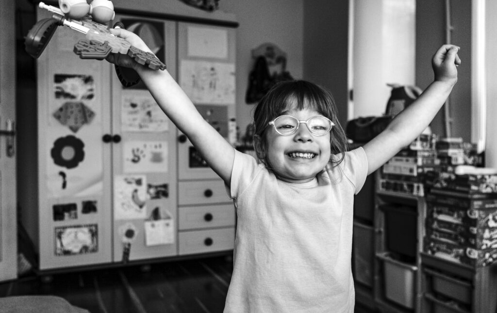 Young girl in glasses raising her arms in glee | Marketing